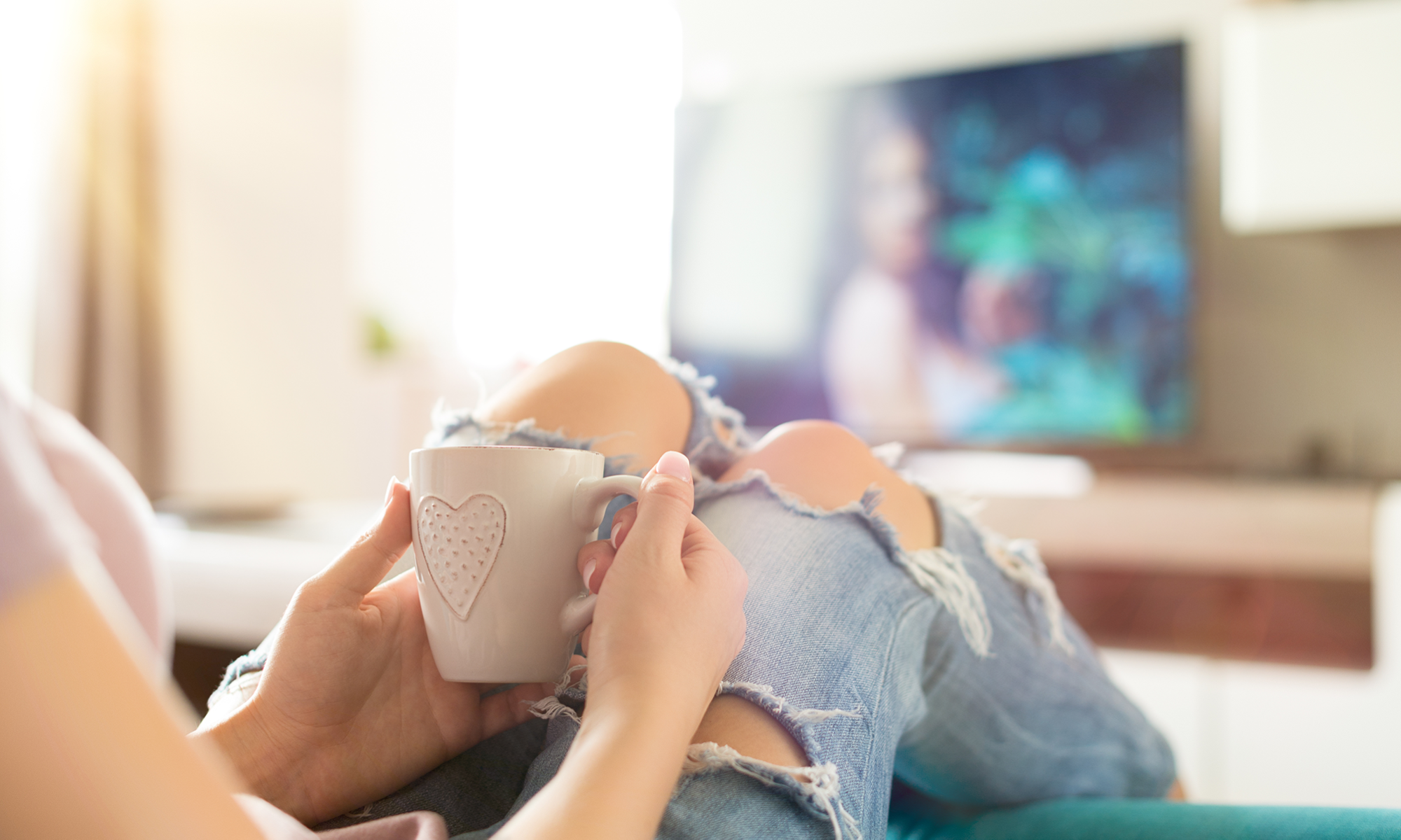 Young woman with a mug watching TV